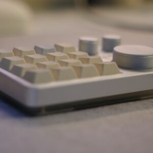A white mechanical keypad with several keys and control knobs.